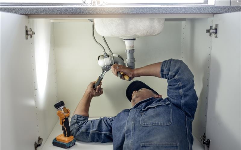 Plumber repairing pipes beneath a bathroom sink in Gardena